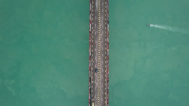 A Boat Passes under the bridge and car passes over the bridge with the blue sea in the background at Barelang Bridge Batam, Indonesia