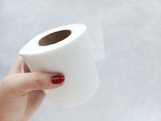 A roll of white paper towels in a woman's hand. Toilet paper on the sleeve. Disposable paper napkins. Hygiene. 