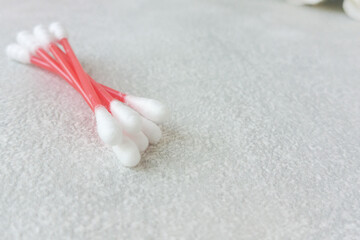 A pile of cotton swabs lies on a gray table, there is a place for text on the side, top view. Hygienic cotton swabs for ears. 