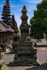 An ancient Balinese temple with tiered pagoda-style roofs and intricate moss-covered stone carvings...