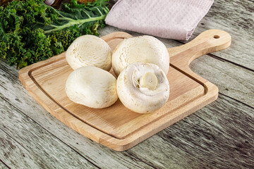 White champignon mushrooms heap over board