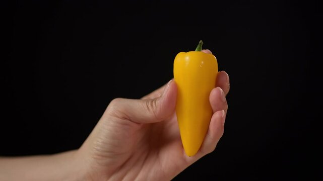 Hand holding a bright yellow pepper kitchen setting food minimalist background close-up view fresh ingredients concept for culinary art