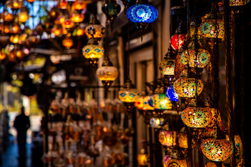 Colorful Turkish mosaic lanterns illuminate a bustling market in Istanbul during Ramadan. The...