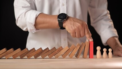 Hand stopping the falling dominos a business crisis management concept for strategic decision...