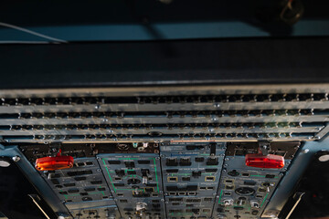 A close up of a control panel with a red button on the top left. The buttons are red and black