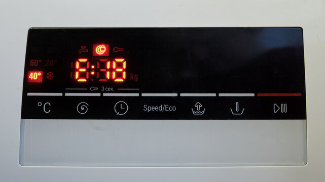 Close-up of a washing machine control panel with a digital display and a error code E18. The red LED screen shows the washing time and temperature settings. Home appliance concept.