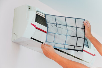 Hand of a man holding dirty air conditioner filter in the white room.