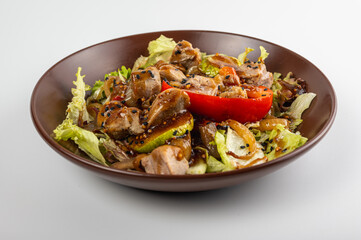 Close-up of a delicious grilled meat salad with fresh lettuce, bell peppers, onions, and sesame seeds. Gourmet dish with juicy pork, perfect for healthy eating