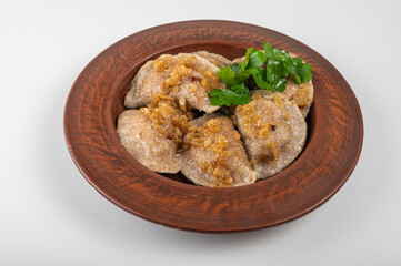 Crispy golden dumplings (varenyky) with sour cream and fresh parsley garnish on a rustic clay plate. Traditional Eastern European cuisine, hearty and delicious	
