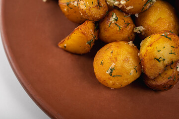 Delicious grilled pork ribs with golden roasted potatoes, pickles, and fresh parsley on a rustic clay plate. Served with creamy white sauce. Perfect homemade meal