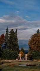 A tranquil and serene garden entrance beautifully framed by vibrant autumn trees against a scenic sky