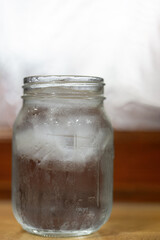Glass of refreshing ice water with condensation droplets on a table near a Winter window with ad or copy space
