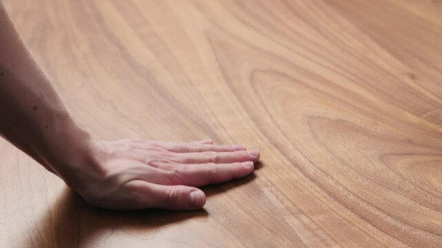 Slow motion man hand touches black walnut dining table surface