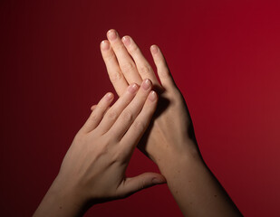 Elegant manicure on female hand with polished nails, beauty and skincare treatment. Stylish, neat, and colorful nail fashion, delicate and attractive gesture, red background.