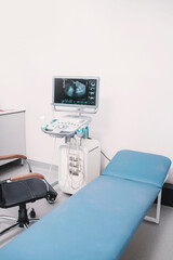 Ultrasound equipment close-up on white background. Modern medical equipment. An ultrasound machine and a couch. Medical equipment background, close-up ultrasound machine. Selective focus
