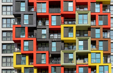 Modern apartment building with colorful facade, glass windows, and balconies. High-rise condominium, urban residential development, luxury living, real estate investment, and comfort..