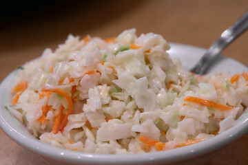 Close up photograph of healthy homemade creamy coleslaw made with cabbage, carrots, mayonnaise salad dressing and served in a bowl
