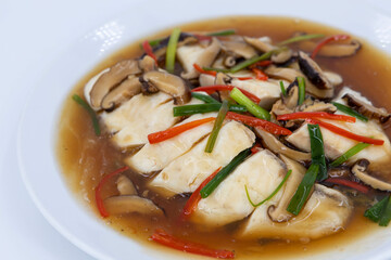 Sea bass fillet steam with soy sauce, Steamed fish in soy sauce broth, garnished with fresh mushrooms, julienned ginger, red chilies, and spring onions, Thaifood