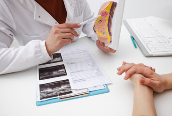 Doctor mammologist shows breast tumor on anatomical model of mammary gland to female patient who...
