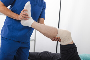 Physical therapist assists patient with leg rehabilitation in a clinical setting. Healthcare...