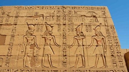 Ancient Egyptian relief sculpture featuring Pharaohs and mythical figures on sandstone walls of archaeological site, cultural heritage