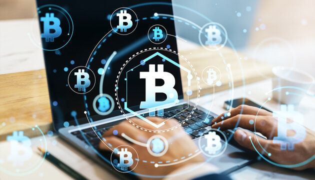 Bitcoin symbols on laptop screen with hologram effect.