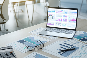 Business financial analysis with charts on laptop screen and printed reports on office desk. 3D Rendering