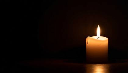 Single candle glowing softly in dark setting, symbol of peace