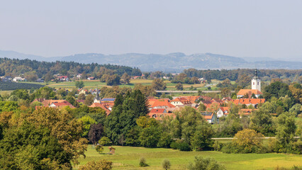 Obraz premium Typical Slovenian villages with white church with red tiles and houses with red roofing in Slovenia during summertime