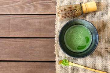 Cup of fresh matcha tea, bamboo whisk and green powder on white wooden table, top view. Space for...