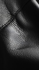 Fototapeta premium Close-up of textured black leather with subtle stitching detail in soft light