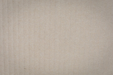 Fototapeta premium Close-up of textured beige corrugated cardboard surface, showcasing vertical ridges and subtle shading..