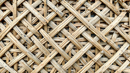 Close-up view of a woven wall or fence.  The material appears to be dried, interwoven straw or reeds, creating a complex pattern of crisscrossing textures.