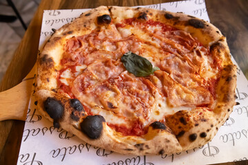 A freshly baked Neapolitan-style pizza topped with thinly sliced ham, melted mozzarella, and tomato sauce. 