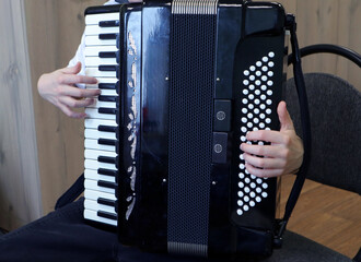 Music school student practices playing the accordion during afternoon lesson in a classroom setting