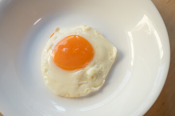Fried egg on white dish close up