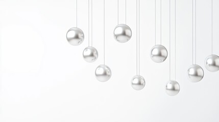 A set of silver metal balls on strings, suspended in the air with empty space at both sides and bottom to create an abstract background. The spheres form a series that have different sizes. 