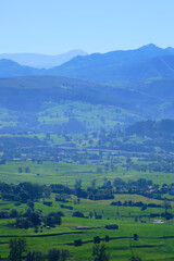 Breathtaking green valley surrounded by misty blue mountains in rural landscape