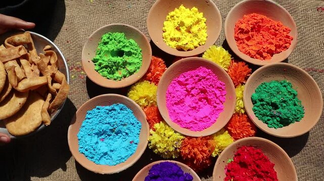 Holi festival setup with vibrant colors in clay bowls and a plate of mathri, a traditional festive snack, symbolizing the joy and culture of Holi celebrations