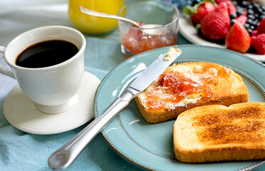A delicious outdoor breakfast with coffee, toast with jam, fresh berries, and orange juice on a beautifully set table. A cozy morning with  a peaceful atmosphere
