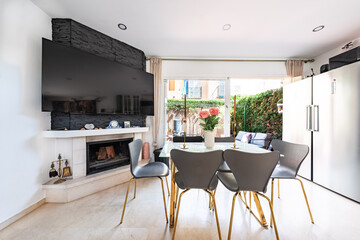 an image of a dining room table next to fireplace and hanging television in mediterranean holiday home 