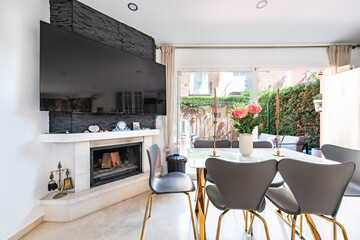 a close up image of a dining room table next to fireplace and hanging television in mediterranean holiday home