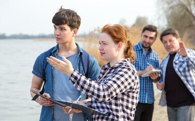 Group of people discuss the problem of the environment near the pond. Practical work for students...
