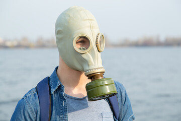 A young man in a gas mask on a summer day. Air pollution by carbon monoxide emissions. Breathe...
