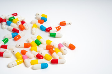 Scattered colorful medicine capsules on isolated white background, vibrant pill assortment. Close up of colorful pills spread out. Health, medication, treatment and variety concept, copy space