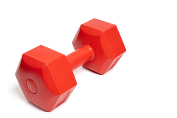 Red hexagonal dumbbell on isolated white background, fitness equipment. Close up of exercise weight dumbbell. Strength, workout, health and exercise concept. Copy space