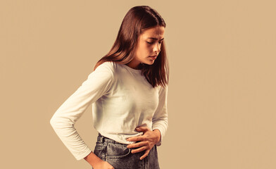 Woman having stomach ache, touching her abdomen, female suffering from menstrual pain or gastrointestinal disease. Woman has abdominal pain isolated on a gray background