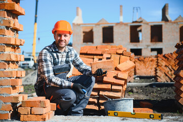 construction mason worker bricklayer installing red brick with trowel putty knife outdoors