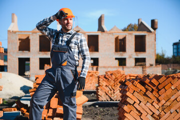 construction mason worker bricklayer installing red brick with trowel putty knife outdoors