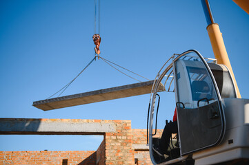 Construction site crane is lifting a precast concrete wall panel to installation building